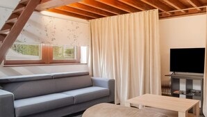 Una sala de estar moderna con un sofá gris, una mesa de madera y un televisor.