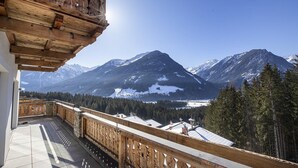Un balcon doté d’une balustrade en bois, d’où l’on peut admirer un paysage montagneux aux sommets enneigés.