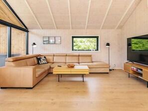 A modern living room with a sectional sofa, a coffee table, a television, and a large window.