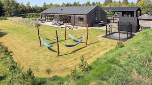 A modern house with a covered patio, a barbecue area, and a hammock. - Holiday Home in Sæby (Sæby)
