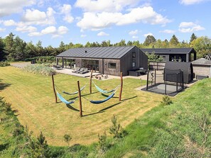 A modern house with a covered patio, a barbecue area, and a hammock. - Holiday Home in Sæby (Sæby)