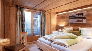 Une pièce en bois avec un lit, une chaise, un bureau et une fenêtre avec des rideaux.