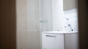 A modern bathroom with a glass shower enclosure, a white sink, and a mirror above it. - Detached Lodge Near Maastricht (Gulpen)