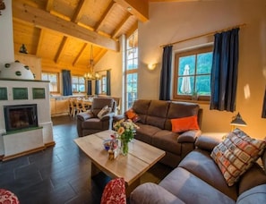 A cozy living room with a fireplace, a sofa, and a dining area. - Cozy Chalet with 4 Bathrooms near Königsleiten (Wald im Pinzgau)