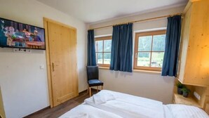 A room with a bed, a chair, and a television on the wall. - Cozy Chalet with 4 Bathrooms near Königsleiten (Wald im Pinzgau)