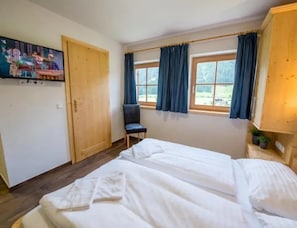 A room with a bed, a chair, and a television on the wall. - Cozy Chalet with 4 Bathrooms near Königsleiten (Wald im Pinzgau)