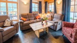 A cozy living room with a wooden ceiling, large windows with curtains, and a central coffee table. - Cozy Chalet with 4 Bathrooms near Königsleiten (Wald im Pinzgau)