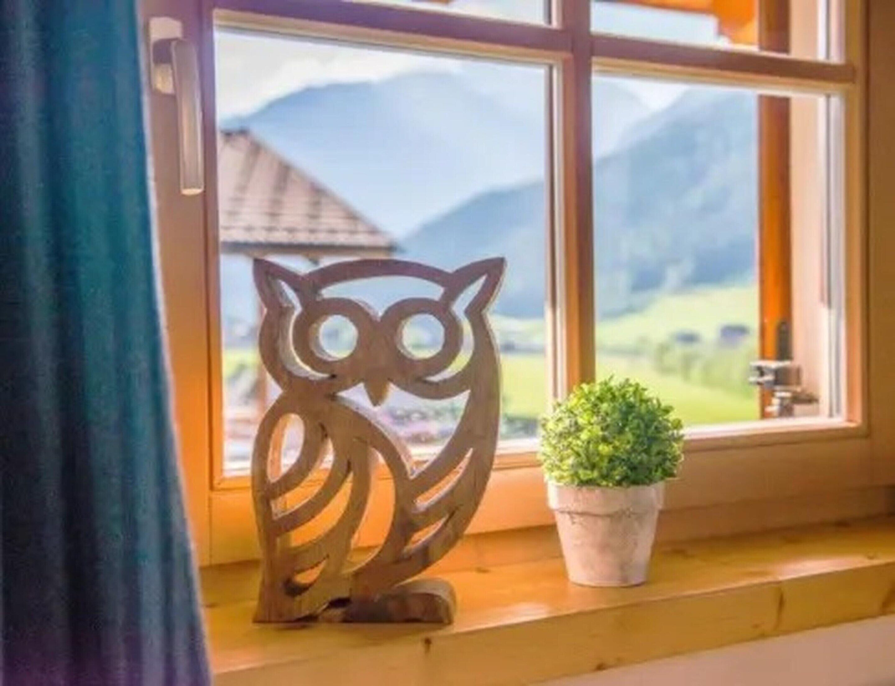 Un rebord de fenêtre orné d’une décoration en forme de hibou en bois et d’une plante en pot.
