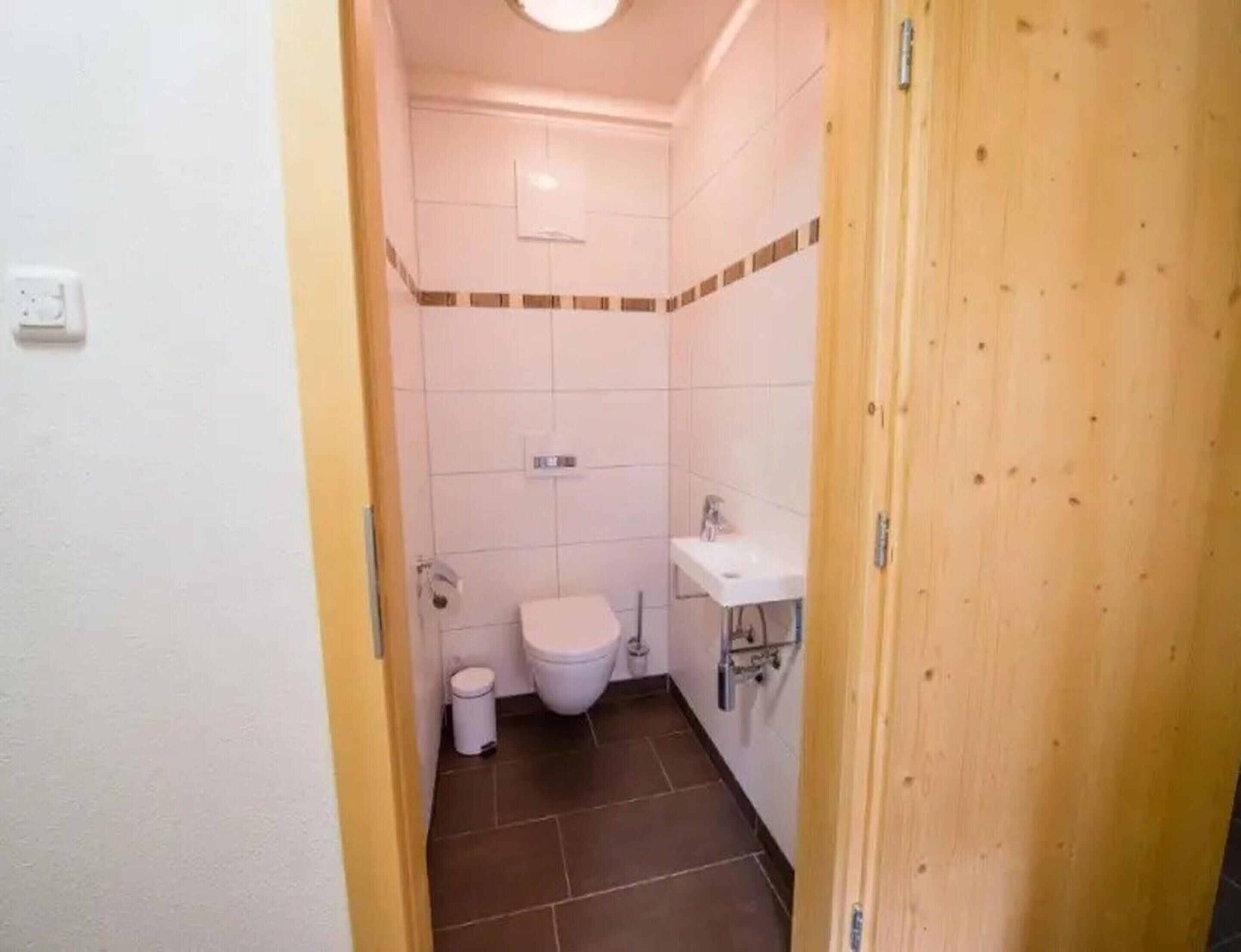 Een kleine badkamer met toilet, wastafel en prullenbak.