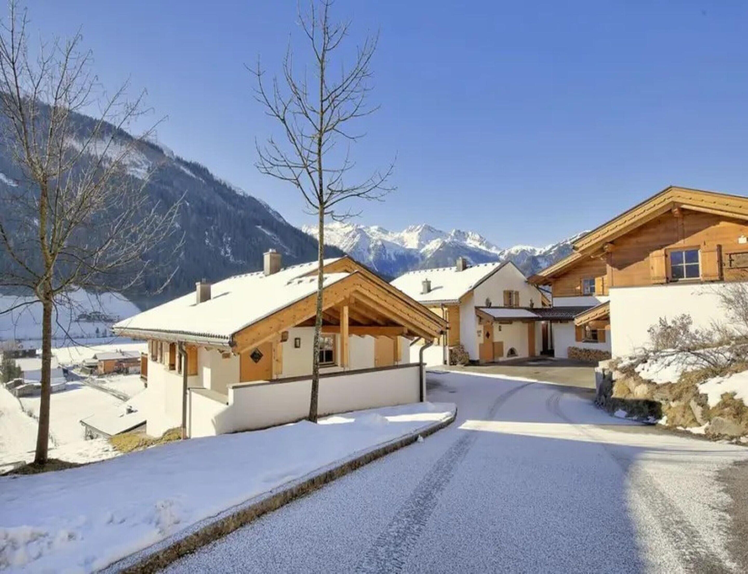 Un village de montagne enneigé, avec des maisons en bois et un ciel dégagé.