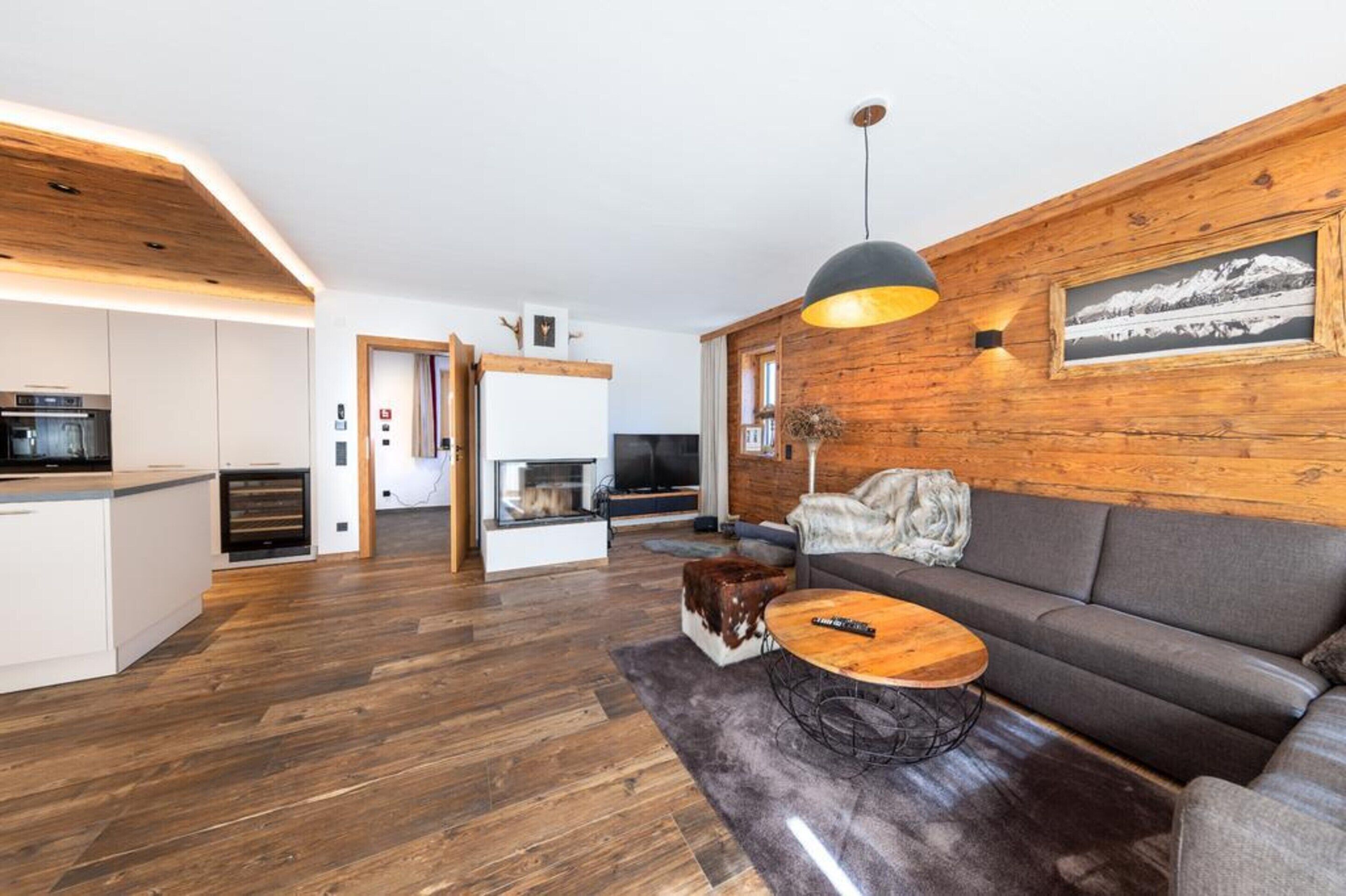 Ein modernes Wohnzimmer mit einer Holzvertäfelung, einer Couch, einem Couchtisch und einem Kamin.