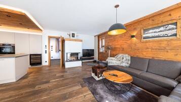 Ein modernes Wohnzimmer mit einer Holzvertäfelung, einer Couch, einem Couchtisch und einem Kamin.