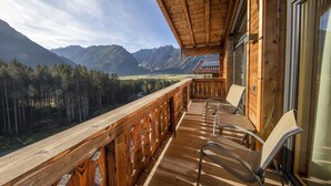 Un balcon en bois offrant une vue sur les montagnes et la forêt.