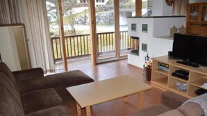 A living room with a sofa set, a coffee table, a television, and a view of the outdoors. - Snug Holiday Home in Wald-Königsleiten near Cross Country (Wald im Pinzgau)
