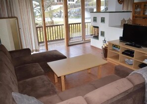 A living room with a sofa set, a coffee table, a television, and a view of the outdoors. - Snug Holiday Home in Wald-Königsleiten near Cross Country (Wald im Pinzgau)