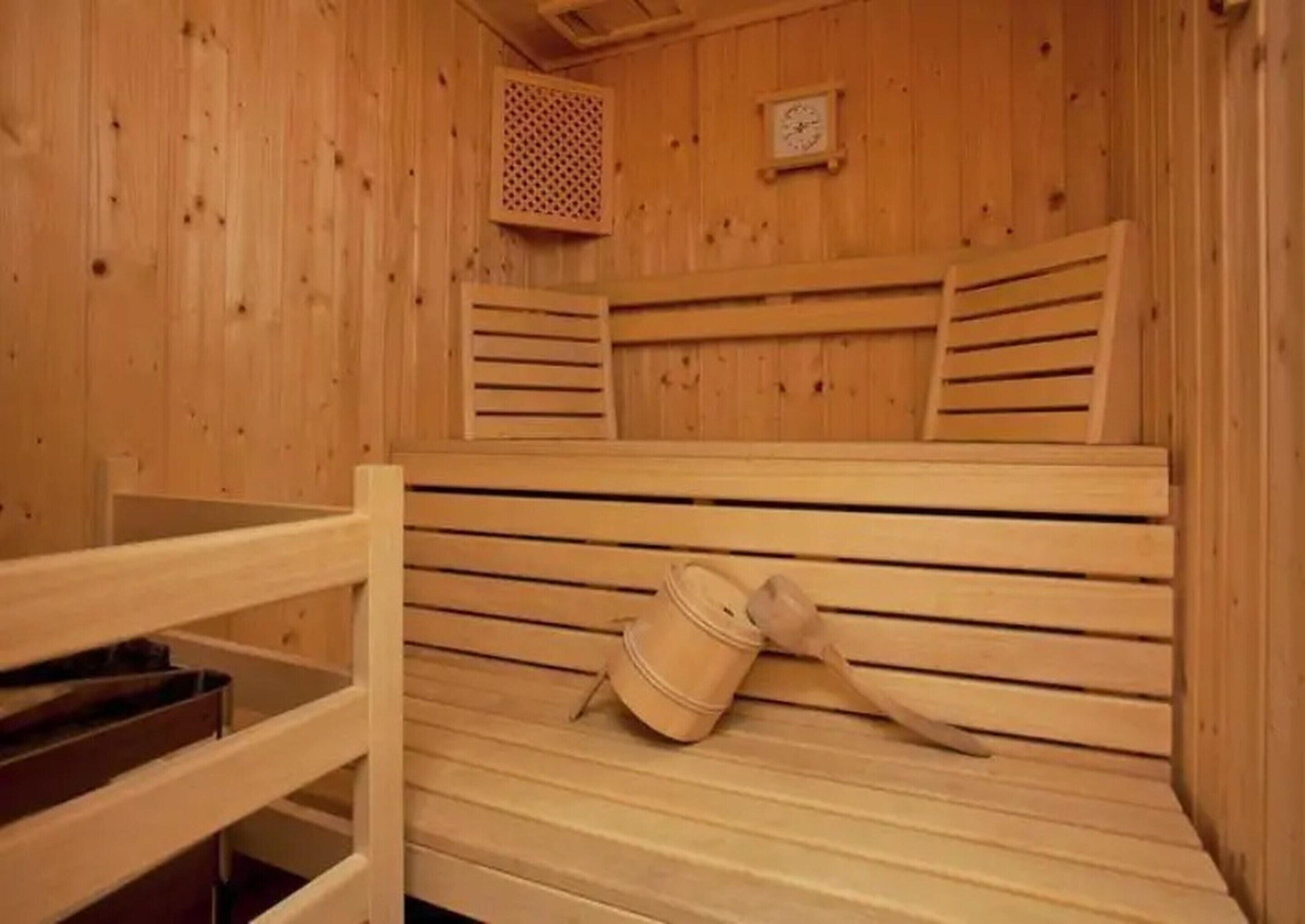 Eine Holzsauna mit Bänken und einem Eimer.