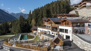 A mountain lodge with a pool, wooden cabins, and a stone wall. - Nationalpark Chalet Hohe Warte (Neukirchen am Grossvenediger)
