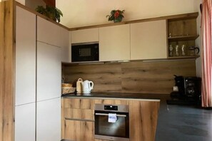 A modern kitchen with wooden cabinets, a built-in microwave, and a coffee machine. - Cozy Chalet with Sauna near Königsleiten (Wald im Pinzgau)