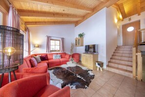 Uma sala de estar com sofá, televisão, armário e escada.