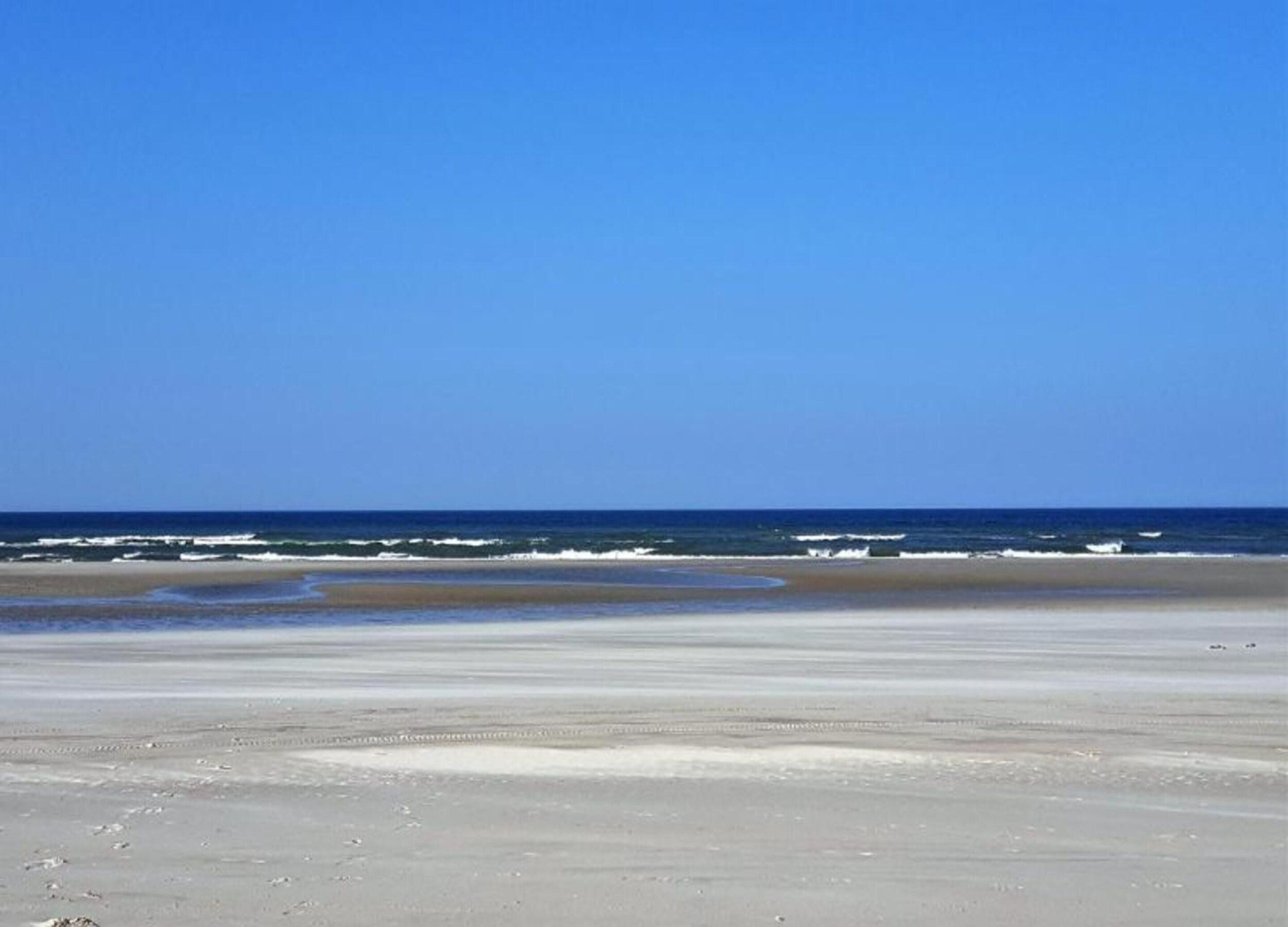 A beach with a clear sky and ocean waves.