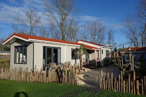 A single-story house with a red roof, a front porch, and a wooden fence.