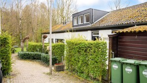 En stig som leder fram till ett hus med ett garage, omgivet av grönska och en klar himmel.
