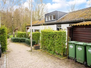 Een pad dat leidt naar een huis met garage, omgeven door groen en een heldere lucht.