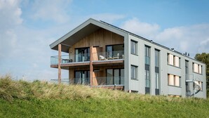A modern two-story building with a balcony, large windows, and a wooden facade. - Apartment in Kamperland With Marina Views (Kamperland)