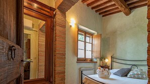 Un dormitorio con una cama, una puerta de madera, una ventana y un radiador.
