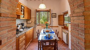 Una cocina con armarios de madera, una mesa de comedor con individuales azules y una lámpara colgante.