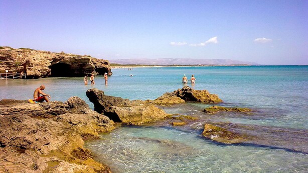 A rocky beach with clear water and a distant mountain range. - Belvilla by OYO Villa Amos (Noto)