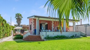 A house with a red exterior, a front porch, and a well-maintained lawn. - Belvilla by OYO Villa Amos (Noto)