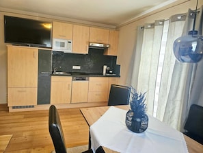 A compact kitchen with wooden cabinets, a microwave, and a dishwasher.