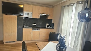 A compact kitchen with wooden cabinets, a microwave, a stove, and a dining area with a table and chairs. - Apartment in Seefeld Near Rosshutte Ski Resort (Seefeld in Tirol)