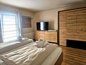 A bedroom with two beds, a TV, a wooden wardrobe, and a radiator. - Apartment in Seefeld Near Rosshutte Ski Resort (Seefeld in Tirol)