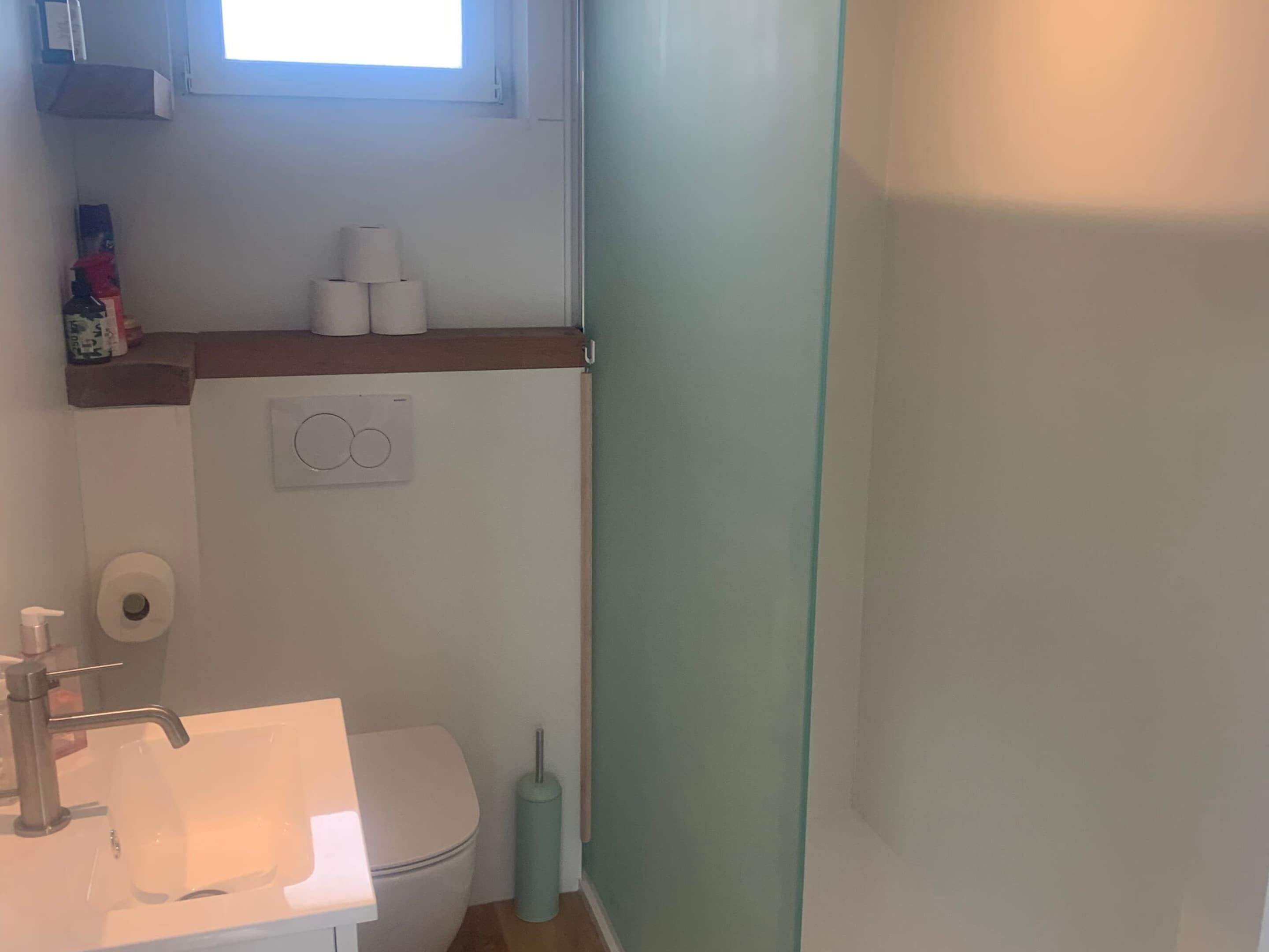 A small bathroom with a toilet, sink, and a window above the toilet.