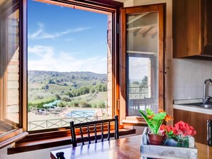 A kitchen with a view of a vineyard and hills. - Rustic Tuscan Stonehouse (Gambassi Terme)