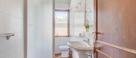 A bathroom with a toilet, sink, and mirror.