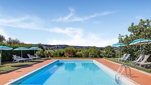 A rectangular swimming pool with clear blue water, surrounded by a tiled deck. There are lounge chairs and umbrellas along the poolside, and a view of the countryside in the background. - Rustic Tuscan Stonehouse (Gambassi Terme)