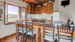 A spacious kitchen with wooden cabinets, a large island with chairs, a built-in oven, and a refrigerator. - Rustic Tuscan Stonehouse (Gambassi Terme)
