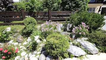 Un jardín con diversas plantas, rocas y una cerca de madera.