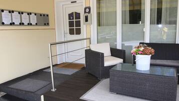 A reception area with a glass coffee table, wicker furniture, a bulletin board, and a door with a keypad.