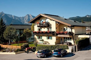 A two-story building with balconies, a carport, and a view of mountains.