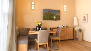 Un coin repas avec une table en bois, des chaises, un vase de fleurs et un tableau accroché au mur.