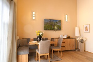A dining area with a wooden table, chairs, a vase of flowers, and a painting on the wall.