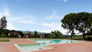 A rectangular pool with a brick patio, surrounded by trees and a view of distant hills. - Varna Charm: Tuscan Getaway (Gambassi Terme)