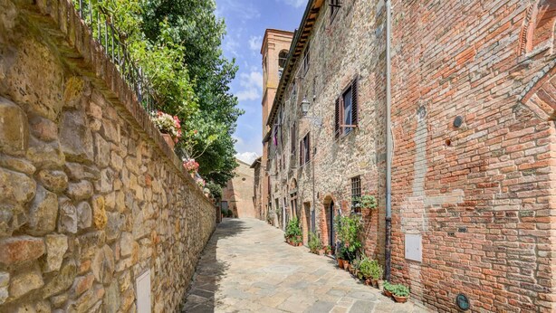 A narrow cobblestone street flanked by stone and brick buildings with small windows and balconies. - Varna Charm: Tuscan Getaway (Gambassi Terme)