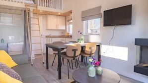 A modern living space with a loft bedroom, a dining area, and a kitchen. - Cozy Tiny House, gas Fireplace, Near Maastricht (Susteren)
