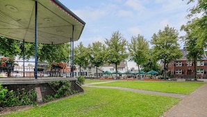 A park with a covered seating area, open grassy spaces, and traditional buildings in the background. - Scenic Escape With Garden (Grubbenvorst)
