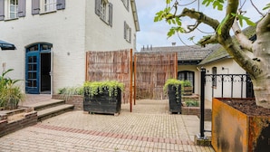 A courtyard with a white building, a blue door, and a bamboo fence. - Scenic Escape With Garden (Grubbenvorst)